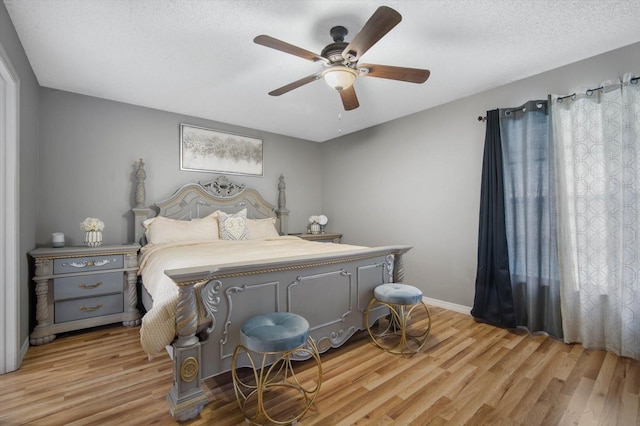 bedroom with a textured ceiling, light hardwood / wood-style floors, and ceiling fan