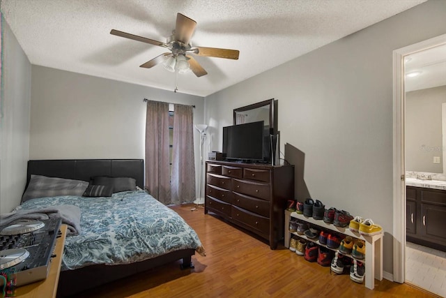 bedroom with light hardwood / wood-style floors, ceiling fan, and a textured ceiling