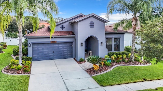 mediterranean / spanish home featuring a front lawn and a garage