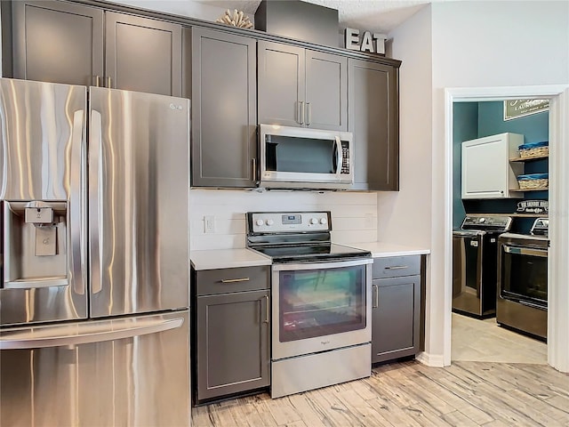 kitchen featuring washing machine and dryer, light wood-type flooring, and appliances with stainless steel finishes