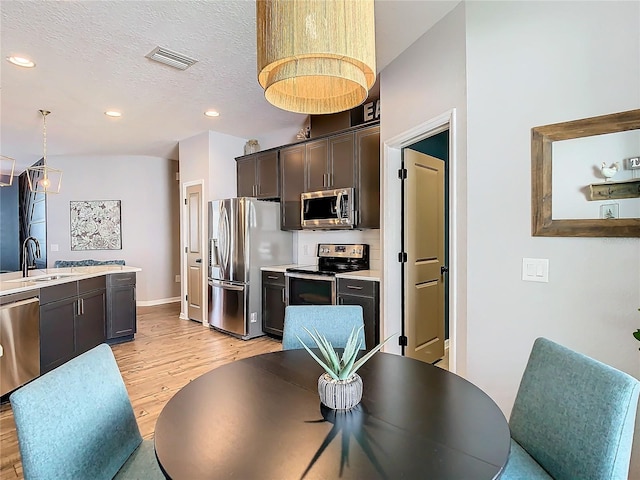 dining room with sink, a textured ceiling, and light wood-type flooring