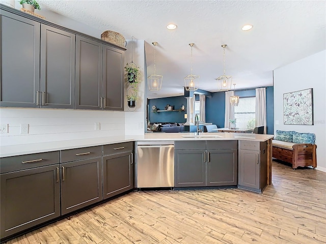 kitchen featuring dishwasher, sink, hanging light fixtures, kitchen peninsula, and light wood-type flooring