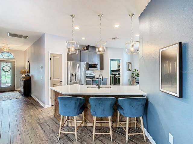 kitchen featuring kitchen peninsula, a kitchen breakfast bar, stainless steel appliances, sink, and decorative light fixtures