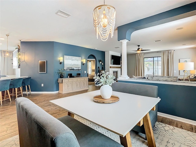 dining room with ceiling fan with notable chandelier and light wood-type flooring