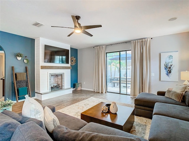 living room featuring ceiling fan, a fireplace, and light hardwood / wood-style flooring