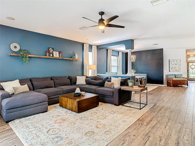 living room featuring ceiling fan, light hardwood / wood-style flooring, and decorative columns