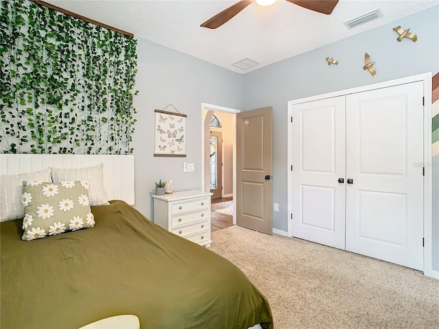 bedroom with ceiling fan, a closet, and light colored carpet