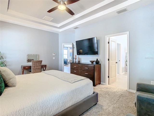 bedroom with a raised ceiling, ceiling fan, and light colored carpet