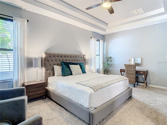 carpeted bedroom with a tray ceiling and ceiling fan