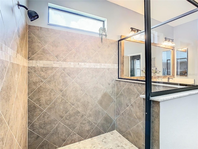 bathroom with tiled shower and vanity