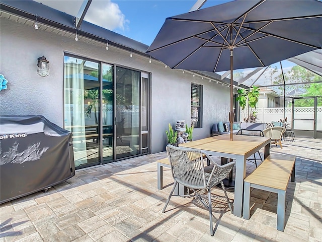 view of patio featuring glass enclosure and area for grilling