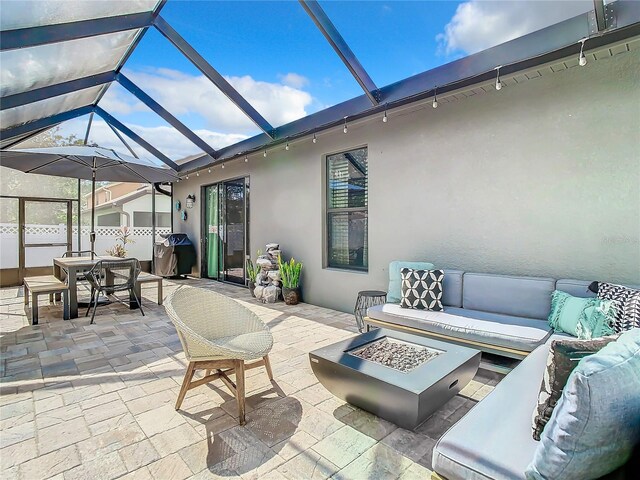 view of patio / terrace with glass enclosure and an outdoor living space with a fire pit