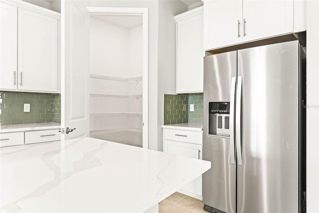 kitchen featuring backsplash, white cabinetry, stainless steel fridge with ice dispenser, and light stone counters