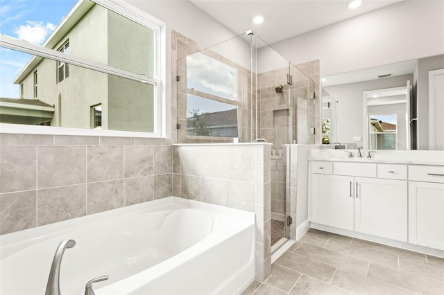 bathroom featuring vanity, plus walk in shower, and a wealth of natural light