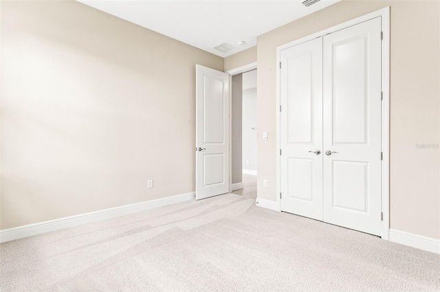 unfurnished bedroom with light colored carpet and a closet