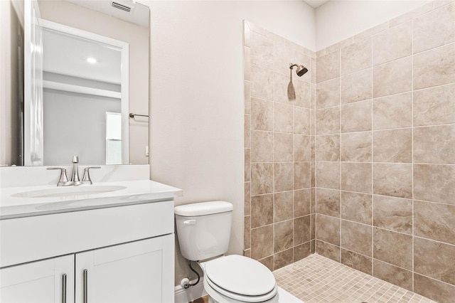 bathroom with tiled shower, vanity, and toilet