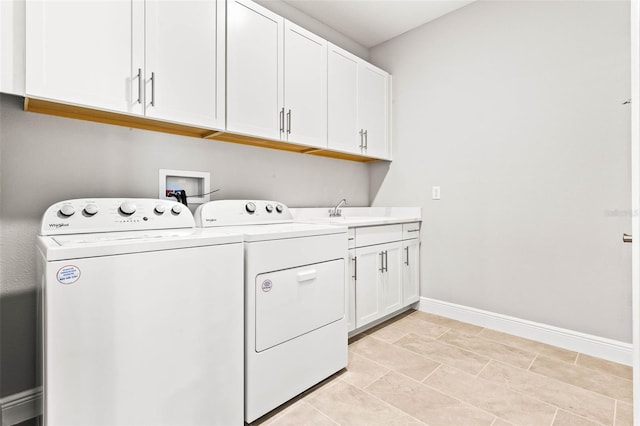 washroom featuring light tile patterned floors, sink, washing machine and clothes dryer, and cabinets