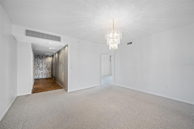 unfurnished room with a notable chandelier, carpet, a textured ceiling, and visible vents