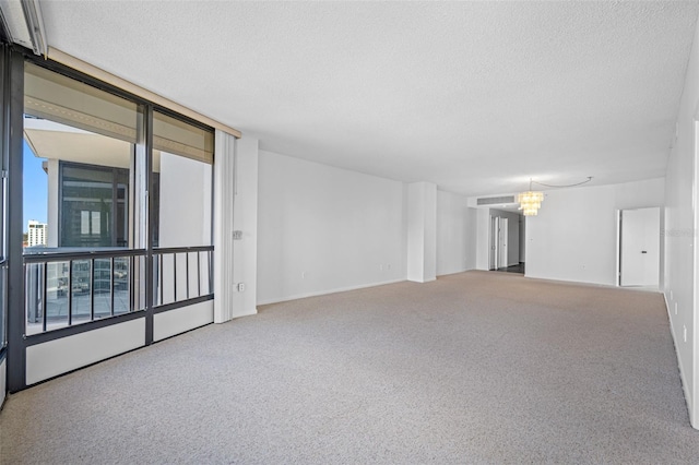 carpeted empty room with a textured ceiling and a chandelier
