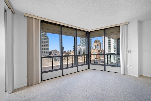 carpeted spare room with expansive windows, a view of city, baseboards, and a textured ceiling