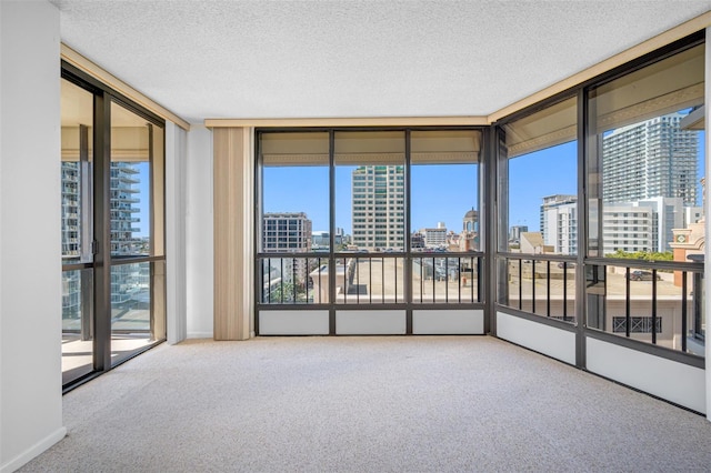 spare room with carpet floors, a textured ceiling, expansive windows, and a city view