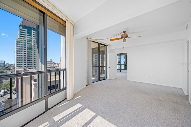 unfurnished room with baseboards, a view of city, a ceiling fan, and carpet floors