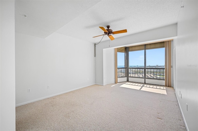 spare room with carpet flooring, a textured ceiling, baseboards, and ceiling fan