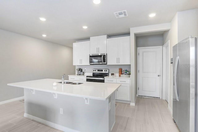 kitchen featuring an island with sink, stainless steel appliances, white cabinets, and sink