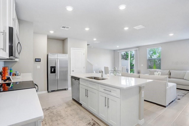 kitchen featuring an island with sink, sink, white cabinetry, appliances with stainless steel finishes, and light hardwood / wood-style floors