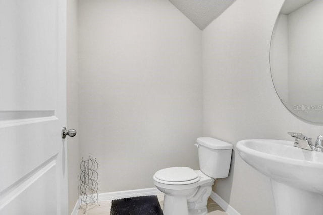 bathroom with vaulted ceiling, sink, and toilet