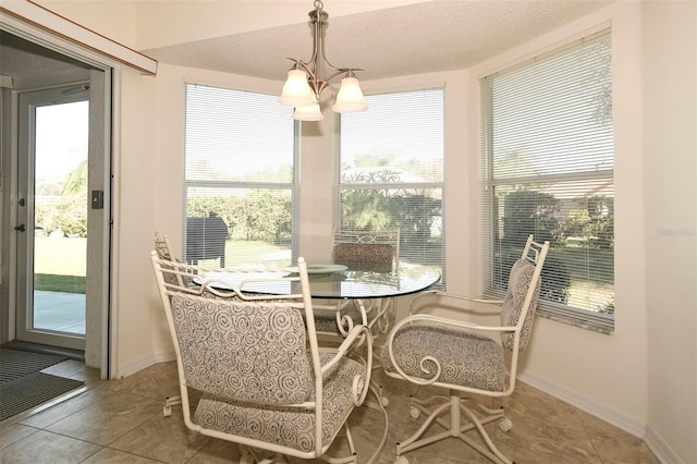 tiled dining area featuring a textured ceiling, a chandelier, and a healthy amount of sunlight