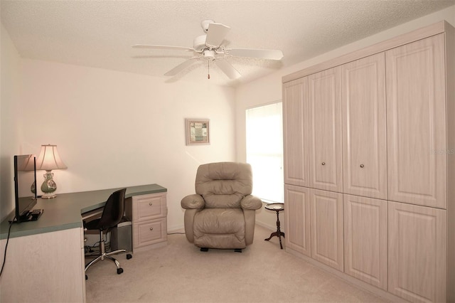 carpeted home office featuring ceiling fan and a textured ceiling