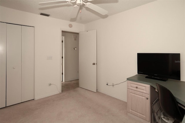 unfurnished office featuring a textured ceiling, ceiling fan, and light colored carpet