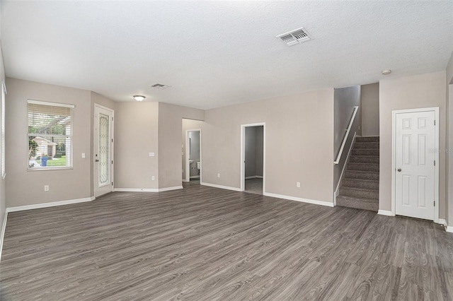 unfurnished living room with a textured ceiling and dark hardwood / wood-style flooring