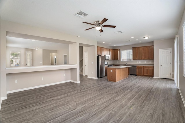 kitchen with ceiling fan, stainless steel appliances, dark hardwood / wood-style flooring, and a kitchen island