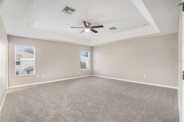 carpeted empty room featuring ceiling fan, a raised ceiling, and a textured ceiling