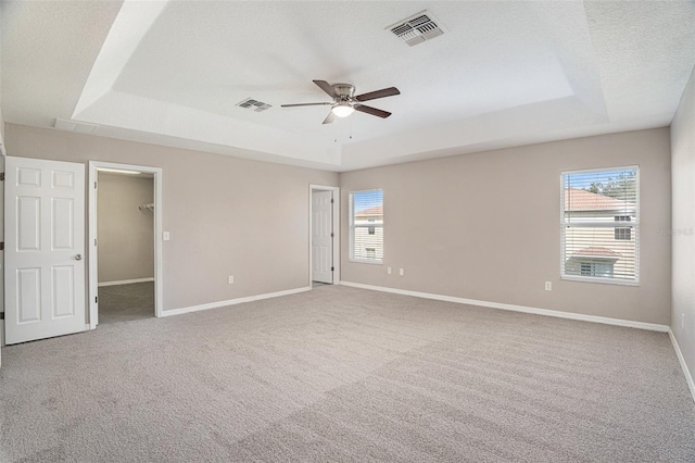 empty room featuring carpet floors, ceiling fan, and a raised ceiling