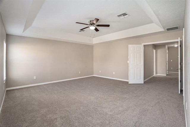 carpeted spare room with a textured ceiling, a tray ceiling, and ceiling fan