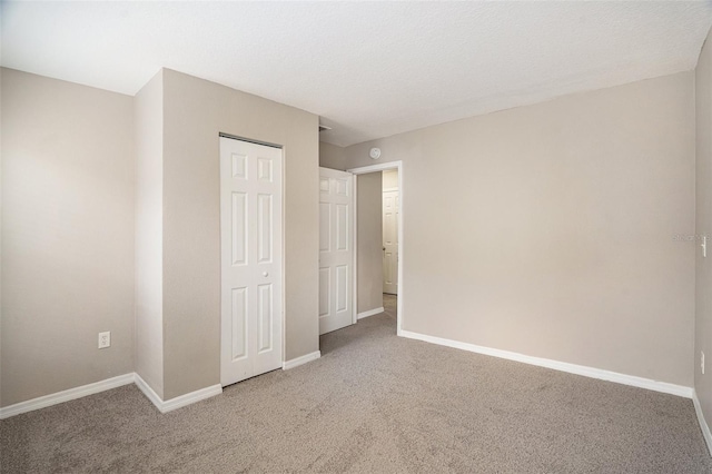 unfurnished bedroom featuring a textured ceiling, carpet floors, and a closet