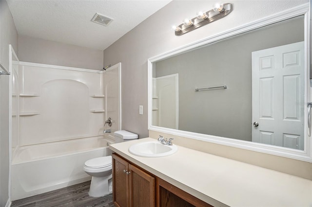 full bathroom with toilet, tub / shower combination, hardwood / wood-style floors, vanity, and a textured ceiling