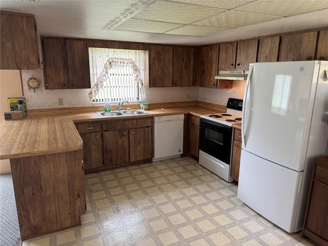 kitchen featuring white appliances, kitchen peninsula, exhaust hood, dark brown cabinets, and sink