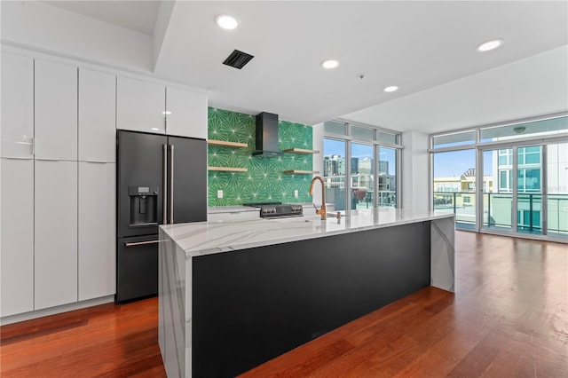 kitchen with stainless steel appliances, white cabinets, a center island with sink, and dark hardwood / wood-style flooring