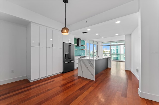 kitchen with dark wood-type flooring, white cabinets, pendant lighting, high quality fridge, and a kitchen island with sink