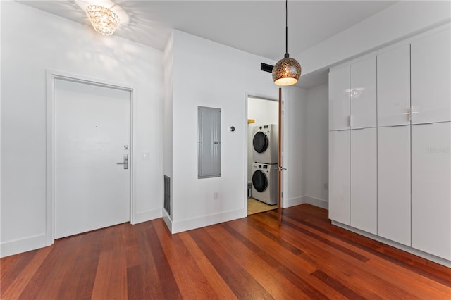 laundry room featuring stacked washer and clothes dryer, hardwood / wood-style flooring, and electric panel