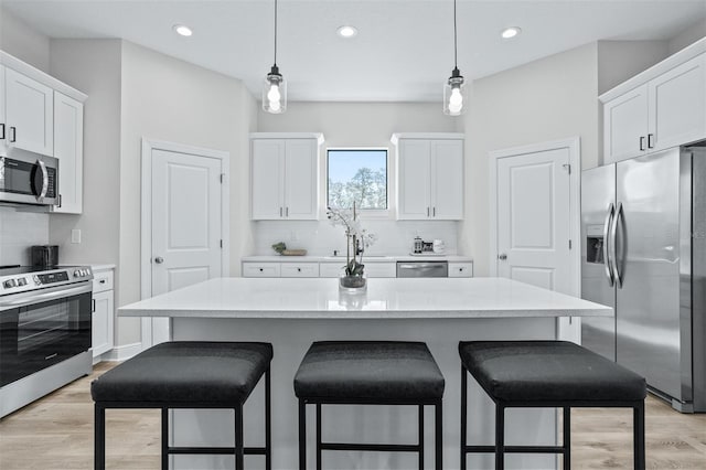 kitchen featuring pendant lighting, stainless steel appliances, white cabinetry, and a kitchen island