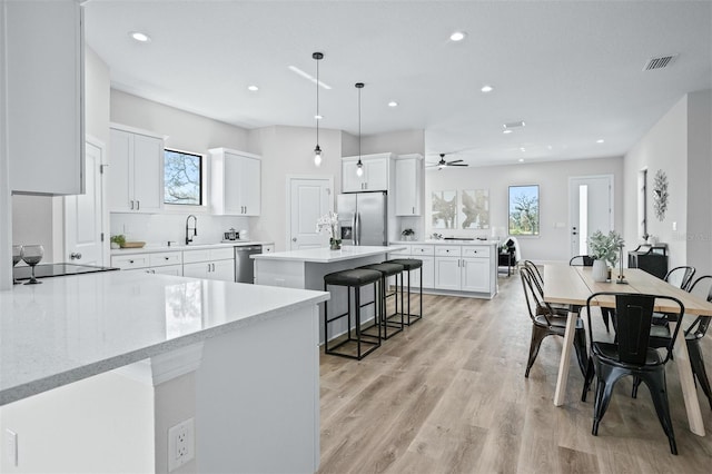 kitchen with white cabinetry, a healthy amount of sunlight, pendant lighting, and stainless steel appliances