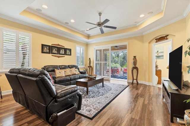 living room with a raised ceiling, crown molding, hardwood / wood-style floors, and ceiling fan