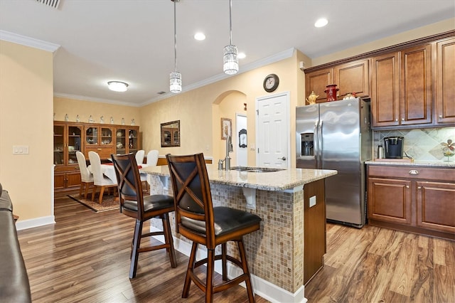 kitchen featuring stainless steel refrigerator with ice dispenser, hanging light fixtures, sink, and hardwood / wood-style floors