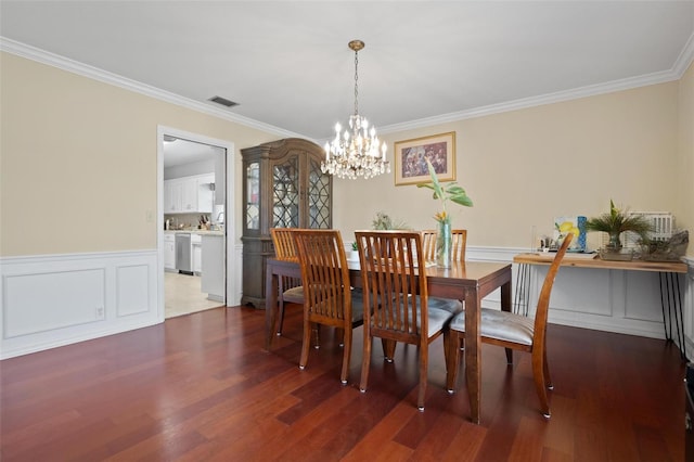 dining area featuring dark wood-type flooring, ornamental molding, and an inviting chandelier