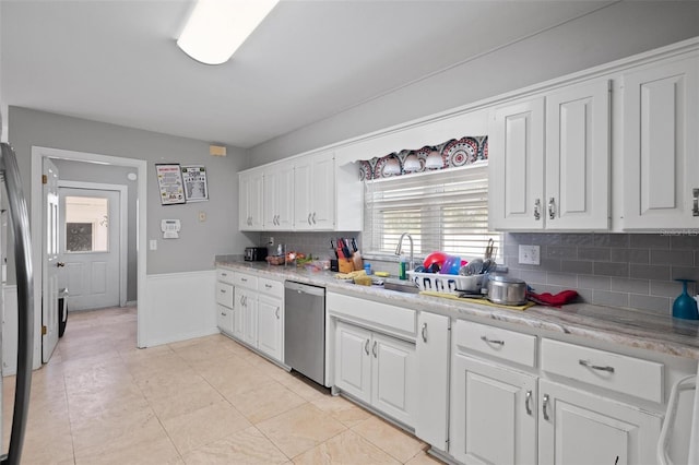 kitchen with light stone countertops, sink, dishwasher, white cabinetry, and decorative backsplash